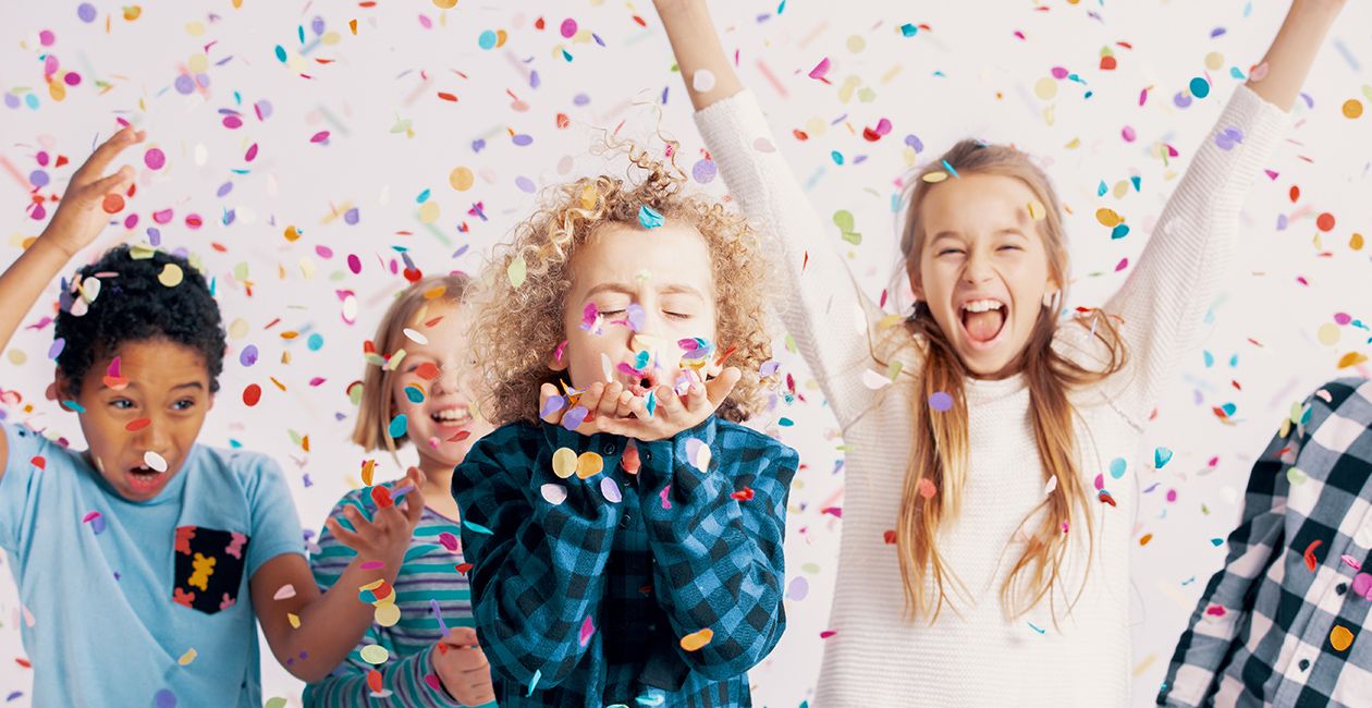 Happy group of kids having fun during birthday party with confetti