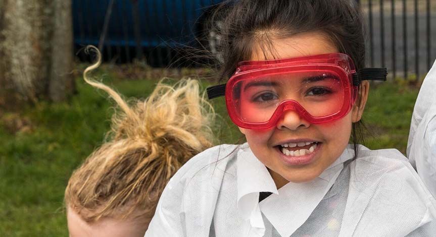 Girl in red safety goggles and a mad science lab coat