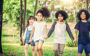 4 happy kids holding hands in the outdoors